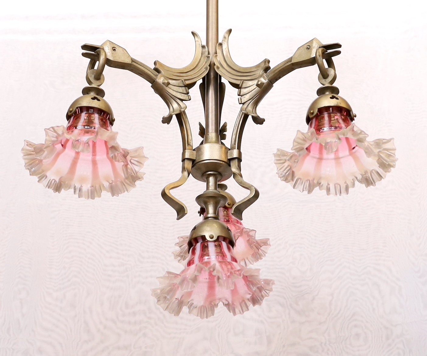 A 1930's Austrian silvered bronze four light chandelier decorated with stylised birds heads, with pink tinted frilled glass shades, height 94cm. width 52cm